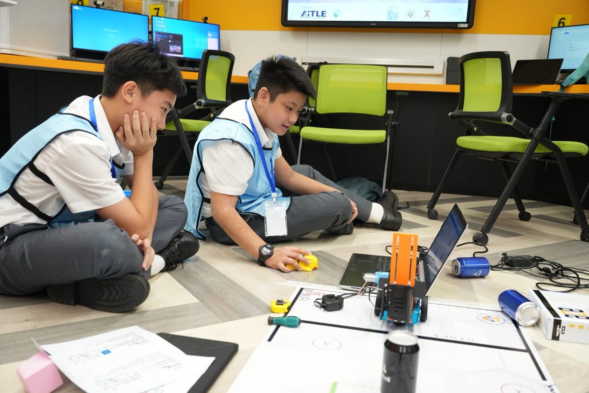 Older students debugging an advanced robot with a laptop at a JBC event